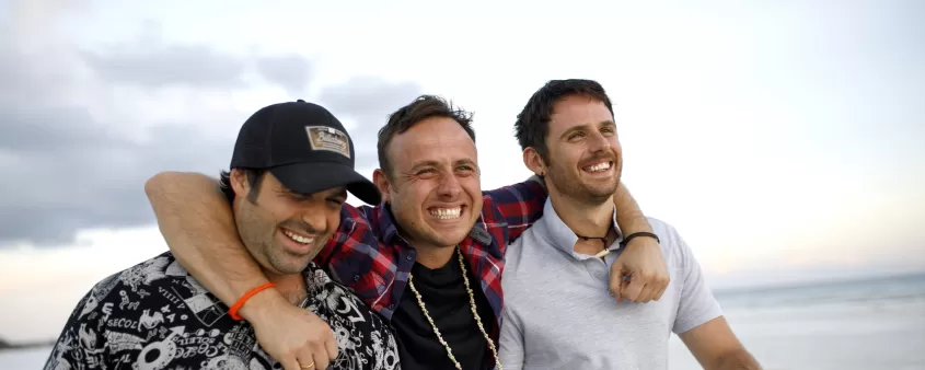A group of men standing next to each other near the ocean